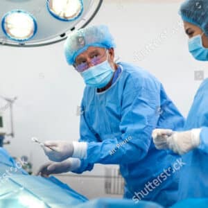 Operating room prep – Surgeon in blue scrubs arranging instruments before procedure