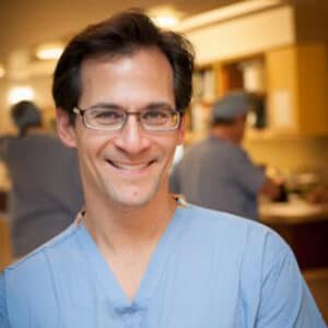 Experienced surgeon in scrubs – Male Alpine Surgical provider smiling in blue uniform