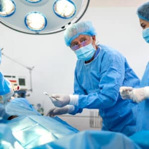 Oral surgeon performing procedure – Medical team in sterile operating room at Alpine Surgical