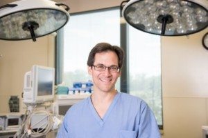 Oral surgeon in Boulder, CO smiling in modern clinic prepared for jaw surgery and implants.
